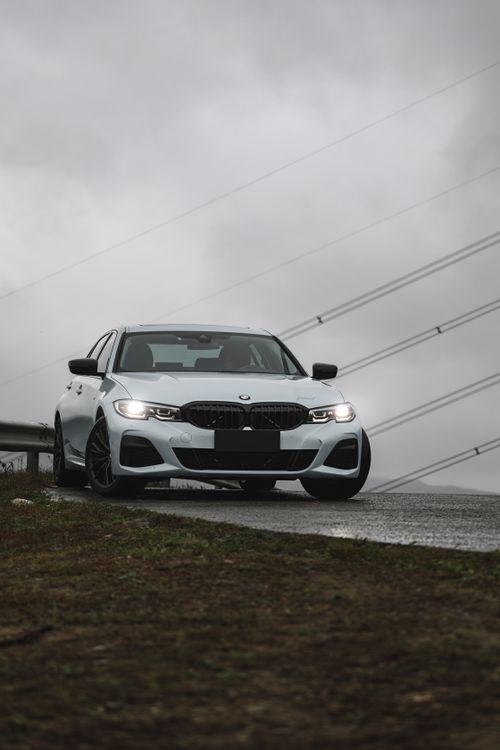Free A sleek white luxury car parked on a road under overcast skies, exuding elegance and style. Stock Photo