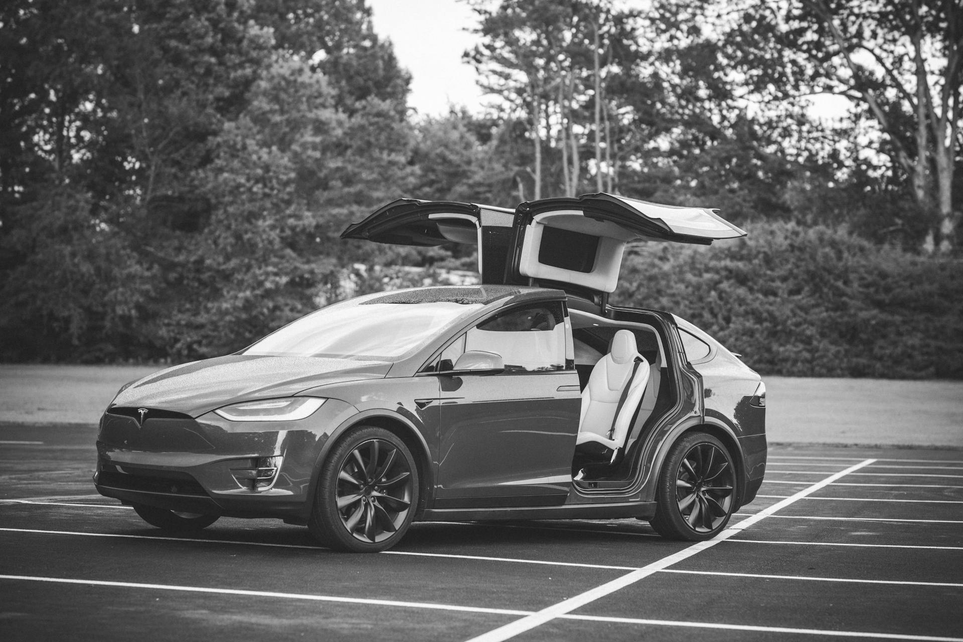 Black and white image of Tesla Model X with open falcon wing doors in a parking lot in NC, USA.