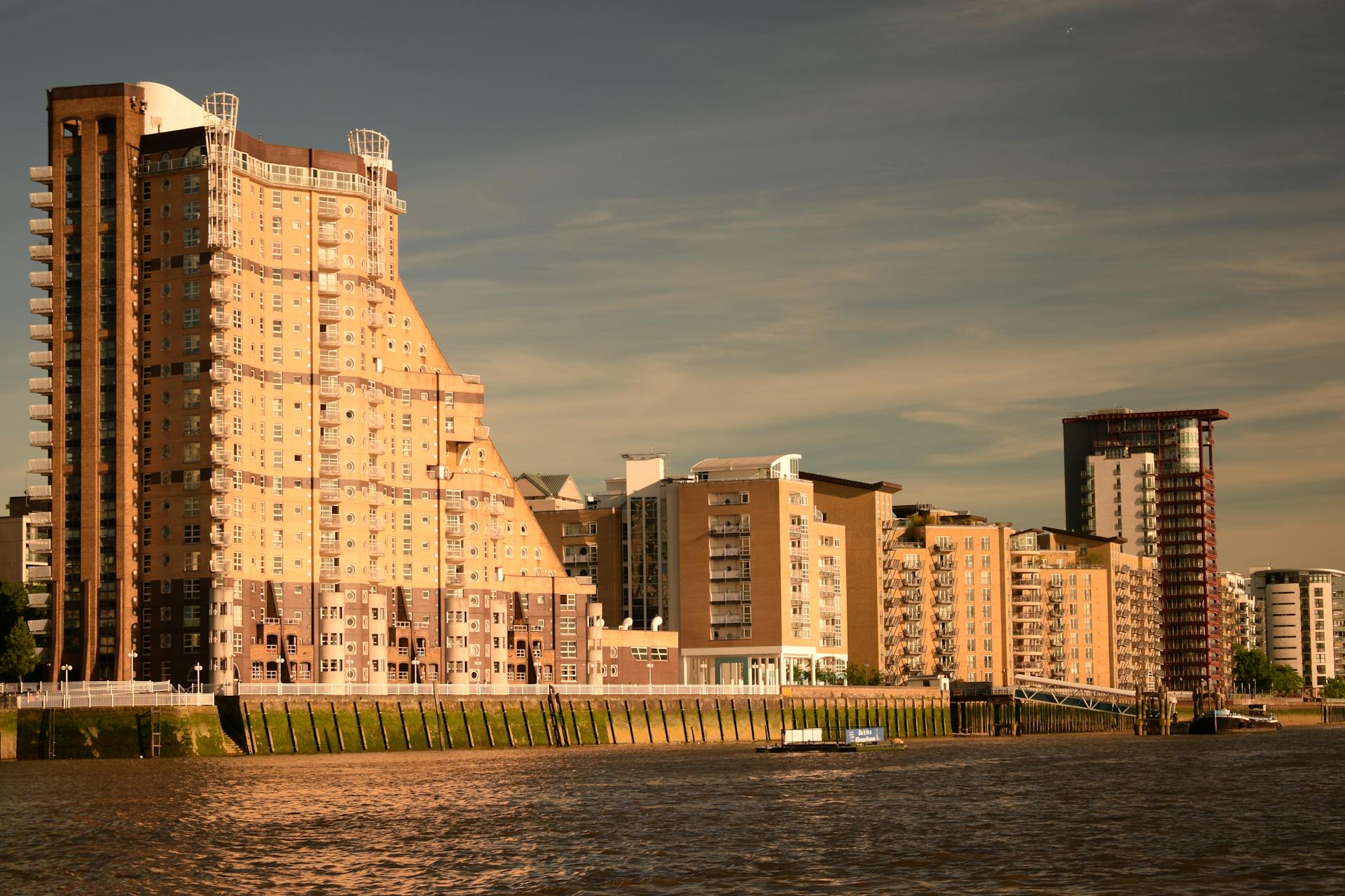 Urban waterfront view featuring modern apartment buildings in London with a river reflection.