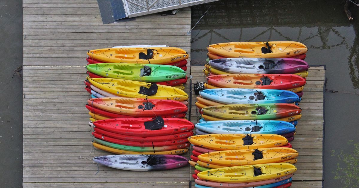 Colorful kayaks neatly stacked on a wooden dock, captured from above.