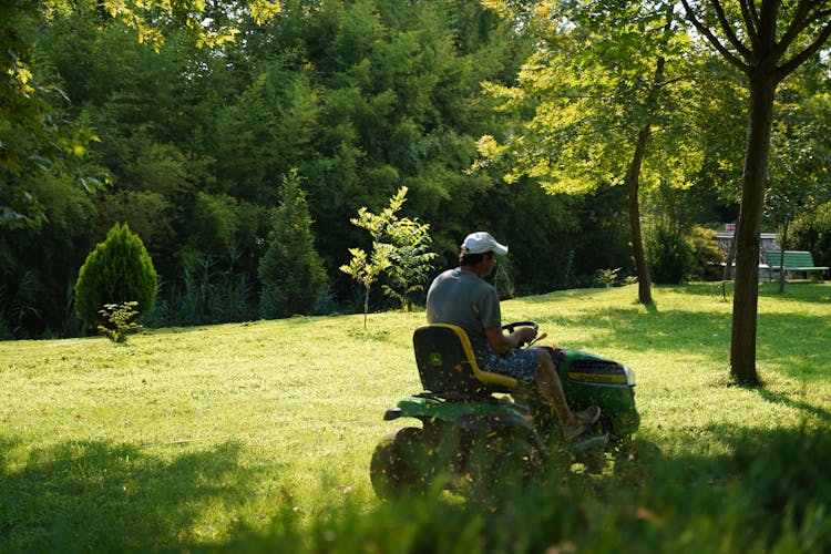 A Man Mowing The Green Lawn