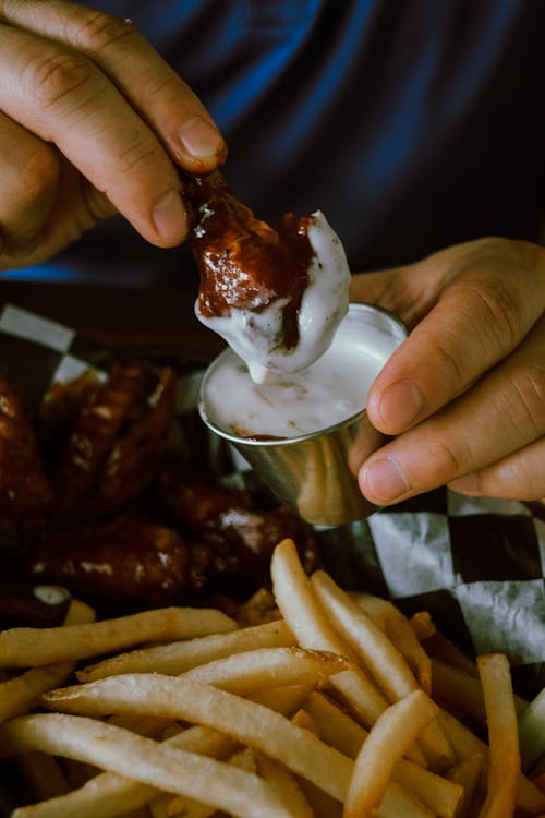 Person Holding Barbecue Chicken with White Sauce