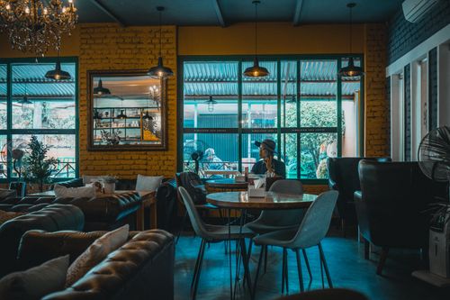 Free Relaxing café atmosphere with a man in a hat using the phone amidst chic interiors. Stock Photo