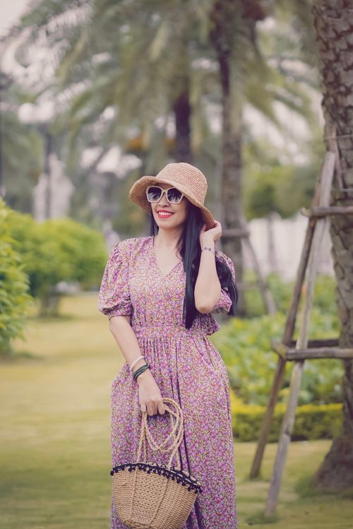 Free Smiling woman in a floral dress and sun hat enjoying a sunny day in a lush park. Stock Photo
