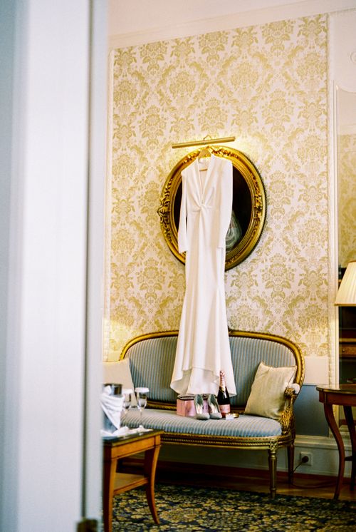 Free A white dress elegantly hanging above a vintage sofa in a luxurious room. Stock Photo