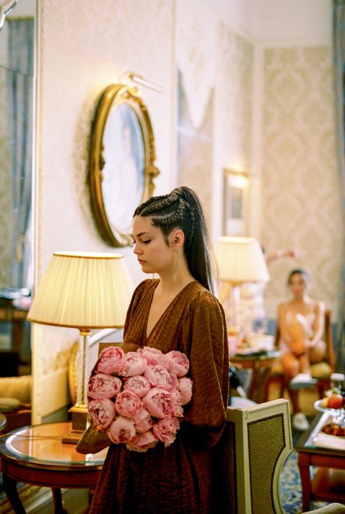 Free Elegant woman with braided hair holding a pink peony bouquet in a luxurious interior setting. Stock Photo