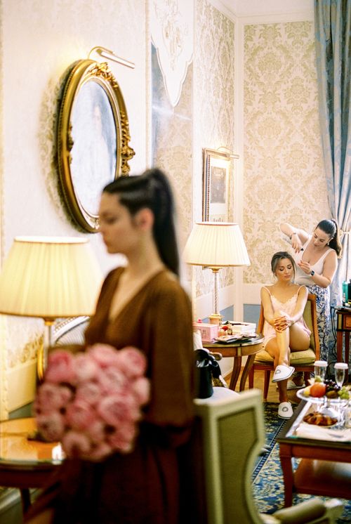 Free Bridal preparation in a luxurious room with stylist and floral bouquet in focus Stock Photo
