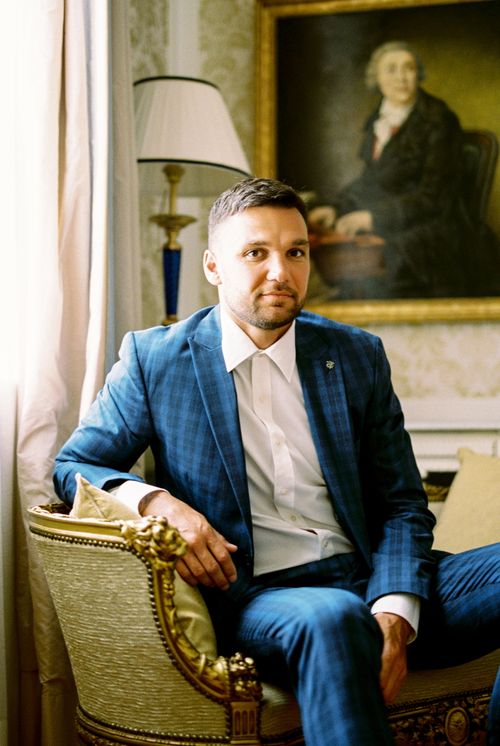 Free Elegant portrait of a man in a blue suit sitting in a lavish armchair with classic decor. Stock Photo