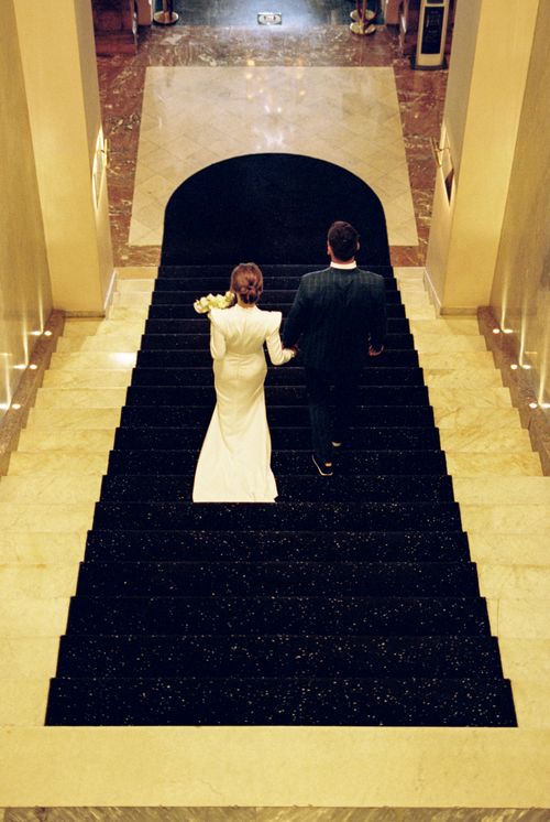 Free Newlywed couple walking down an elegant staircase, capturing a classic wedding moment. Stock Photo