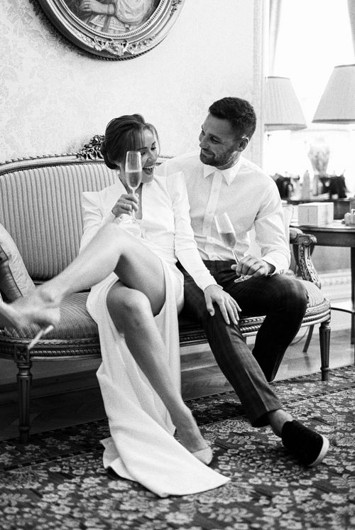 Free A sophisticated couple relaxes with champagne on a vintage sofa, capturing a timeless moment. Stock Photo