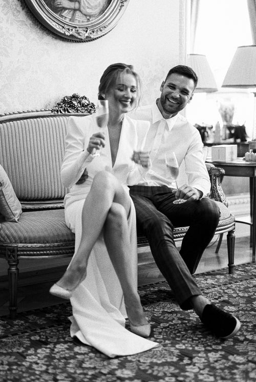 Free A joyful couple sitting on a sofa, enjoying champagne and laughter indoors. Stock Photo