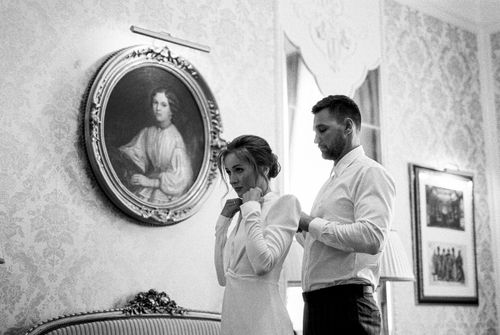Free A monochrome photo of a couple getting dressed together in a vintage interior setting. Stock Photo
