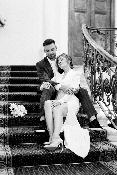 Free A bride and groom in an intimate pose on a staircase during their wedding day. Stock Photo