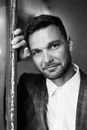 Black and White Portrait of Groom Leaning Against Door Frame