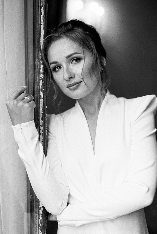 Free Black and white portrait of a woman in a white dress leaning against a door frame. Stock Photo