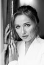 Black and White Photo of Woman Holding Onto Door Frame
