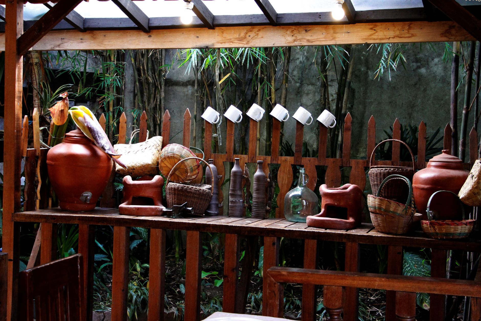 Charming outdoor setup with baskets and vases on a wooden shelf in a bamboo garden.