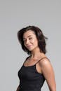 灰色背景下黑色上衣的微笑黑发女人，工作室肖像