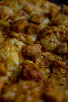 A mouthwatering close-up shot of cheesy chicken pizza with herbs.