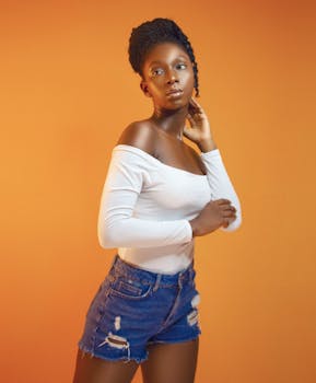 Portrait of a fashionable young woman posing confidently with an orange backdrop.