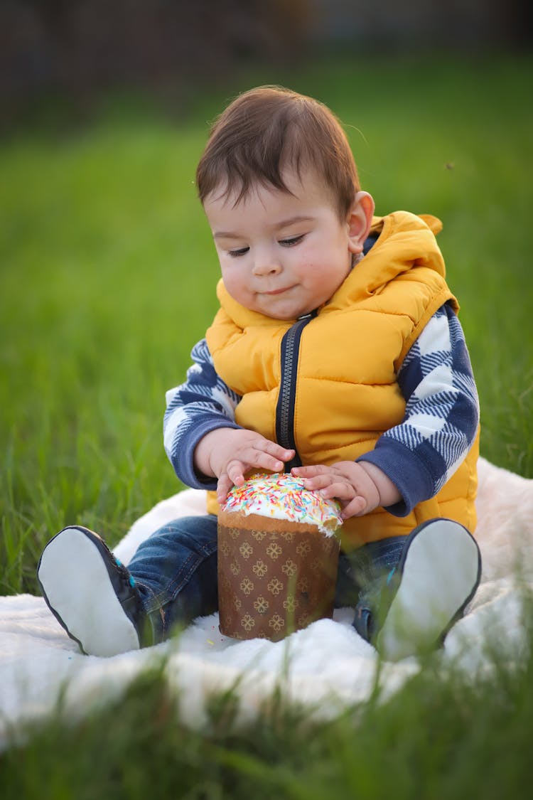 Toddler Playing With A Toy While Sitting On A Blanket