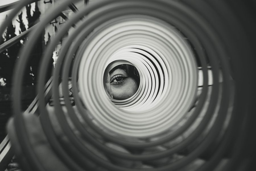 Artistic black and white photo featuring an eye through a spiral structure, emphasizing perspective and focus.