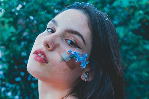 Free A Beautiful Woman with Band Aid and Flowers on Her Face Stock Photo