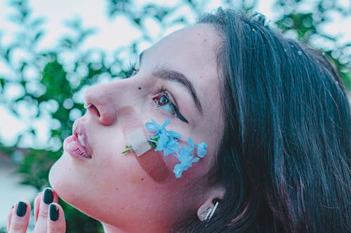 Woman With Bandage and Blue Flower on Face 