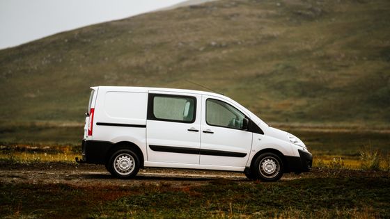 White panel van parked side-on beside a grassy hillside. Photo by Till Daling on Pexels