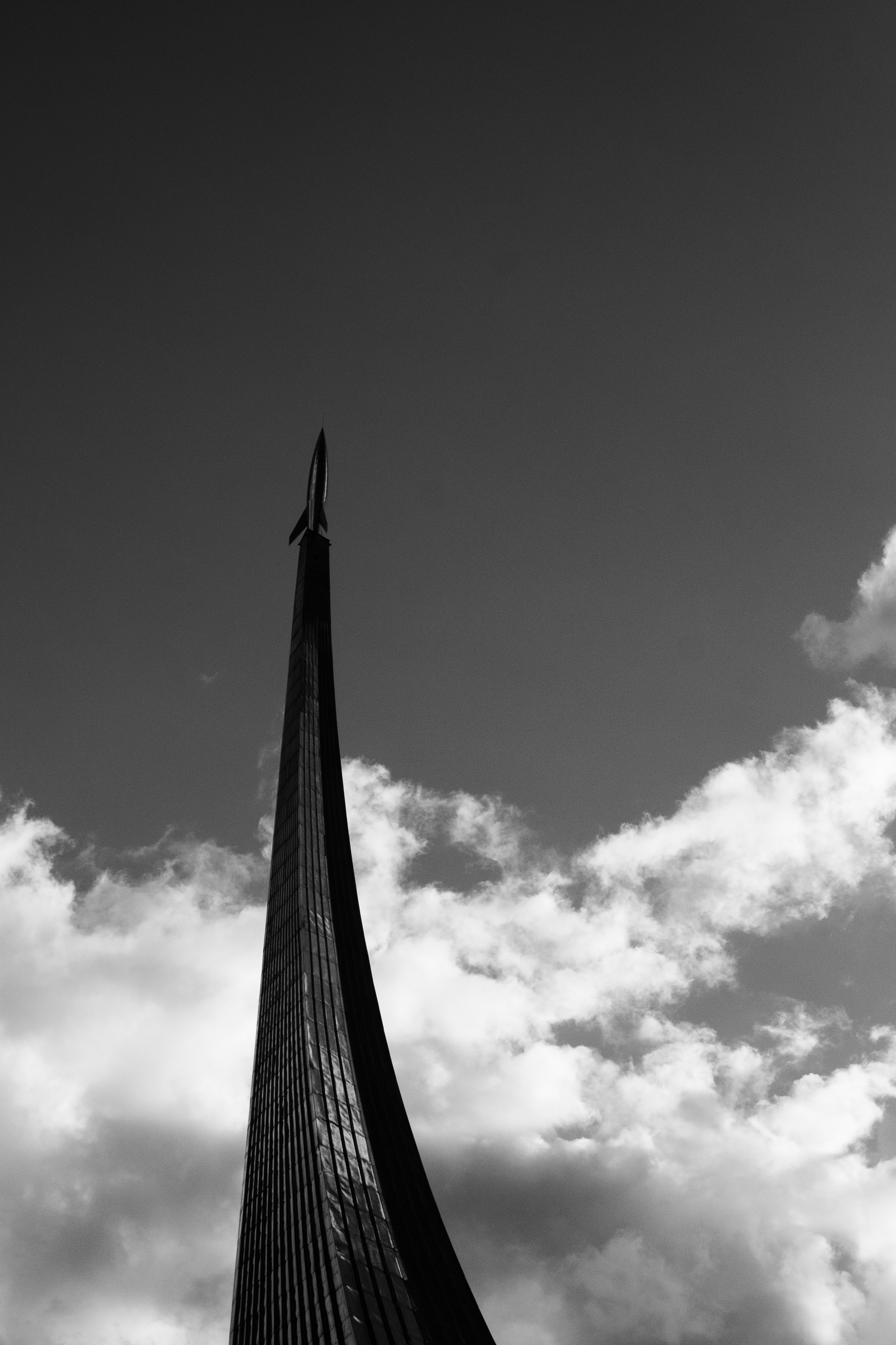 Elegant shot of a sleek monument reaching into a cloudy sky, in black and white.
