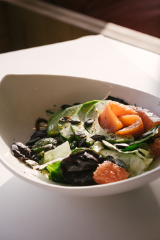 Close-up of a fresh vegetable salad with salmon and avocado in natural light.