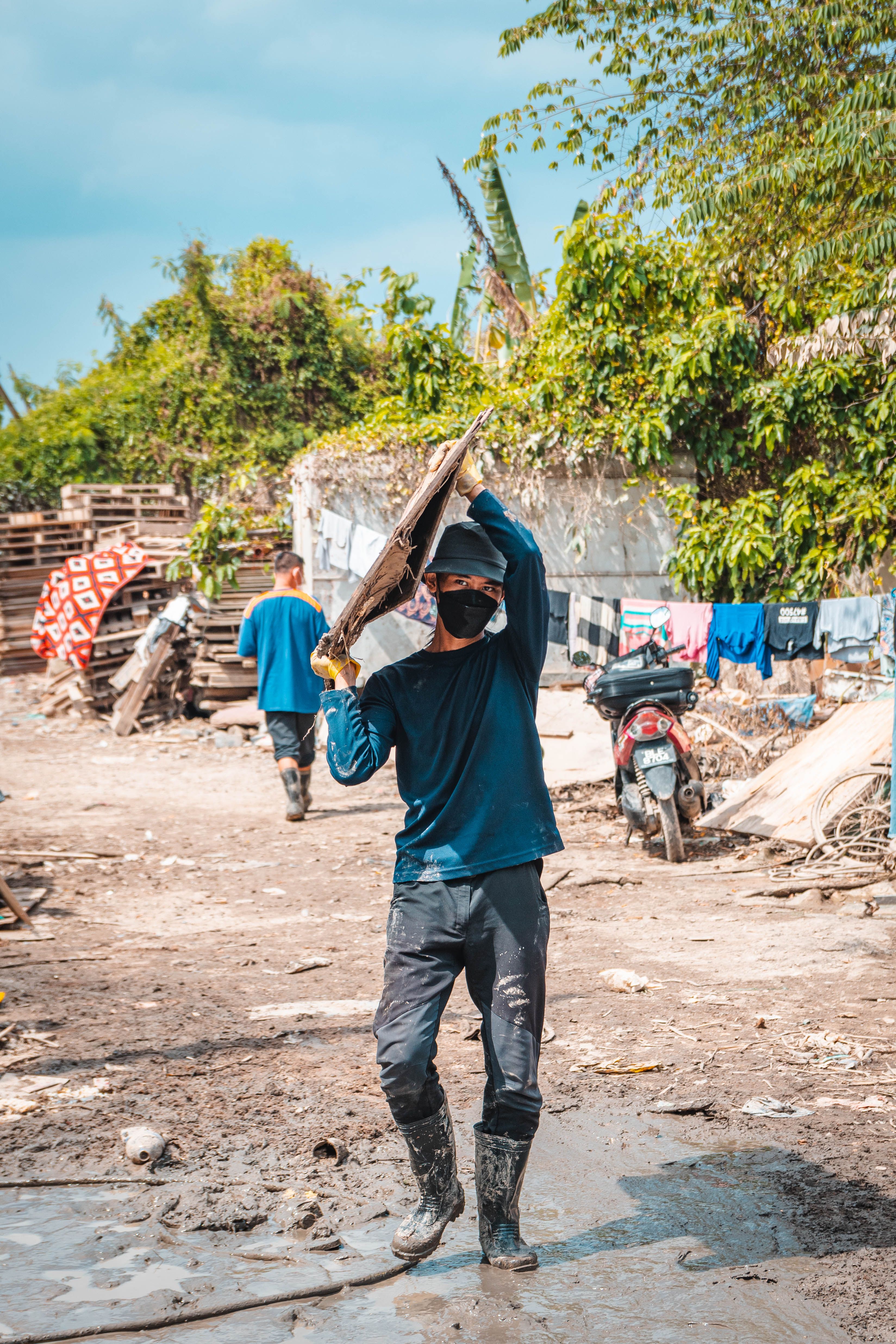 A person wearing a dust mask while gardening, with sunlight filtering through the trees