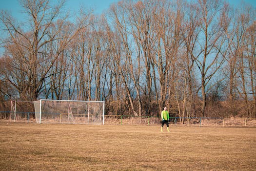 A young soccer player in a lime green jersey stands on an autumn field in Slovakia.