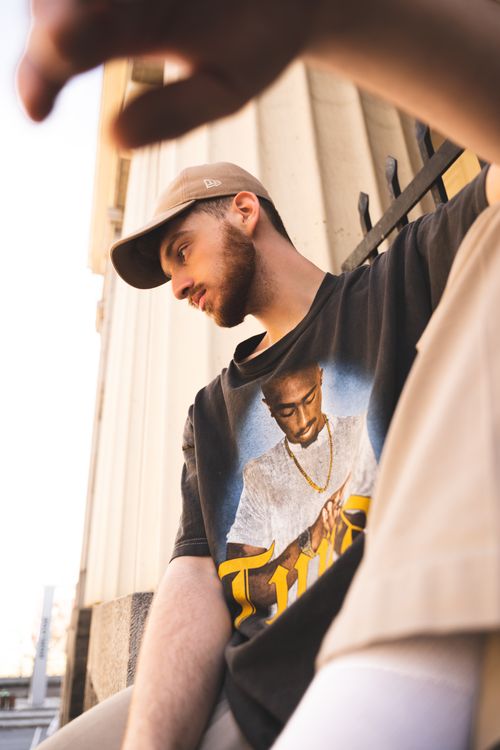 Free Candid outdoor shot of a young bearded man in casual streetwear against a building backdrop. Stock Photo
