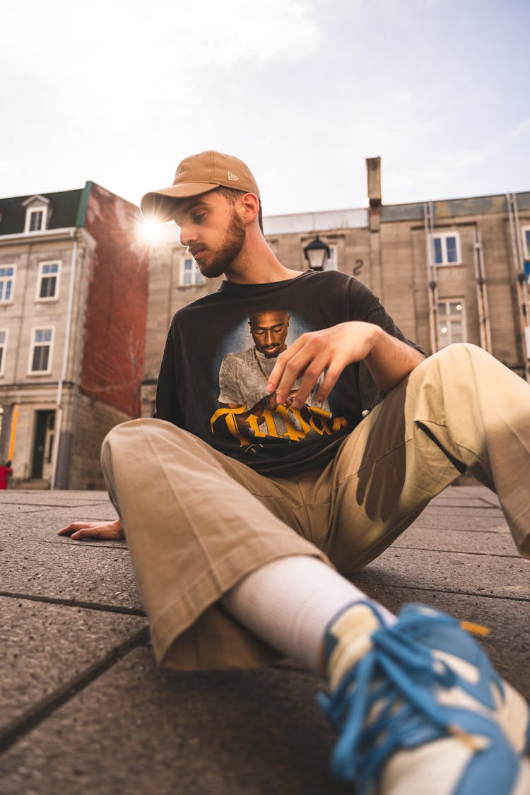 Low Angle Shot Of A Man Sitting On A Sidewalk