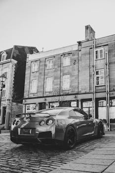 A stylish sports car parked on a cobbled street with classic urban architecture.