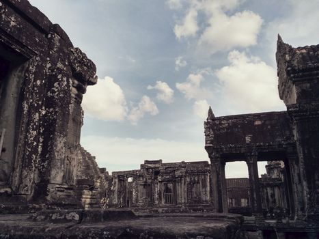 Weathered stone ruins set against a cloudy sky, showcasing ancient architecture.
