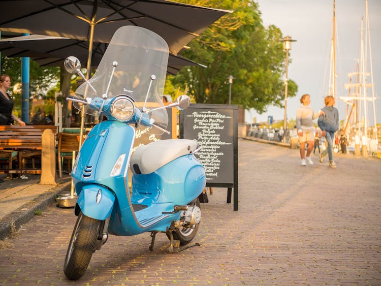 A Blue Vespa With Windshield