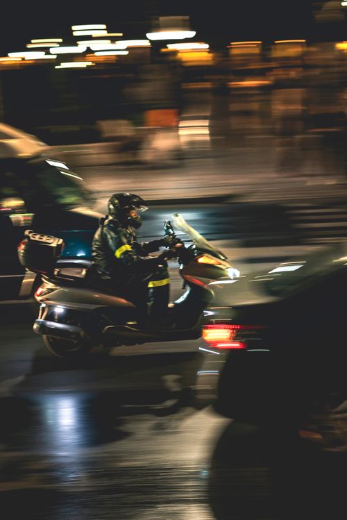 Free A person riding a motorcycle on a city street at night with motion blur effect. Stock Photo