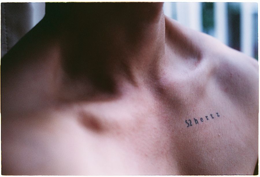 Fine-line script tattoo across a collarbone