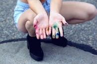 Woman Squatting Holding Out Her Hands With Assorted Paints