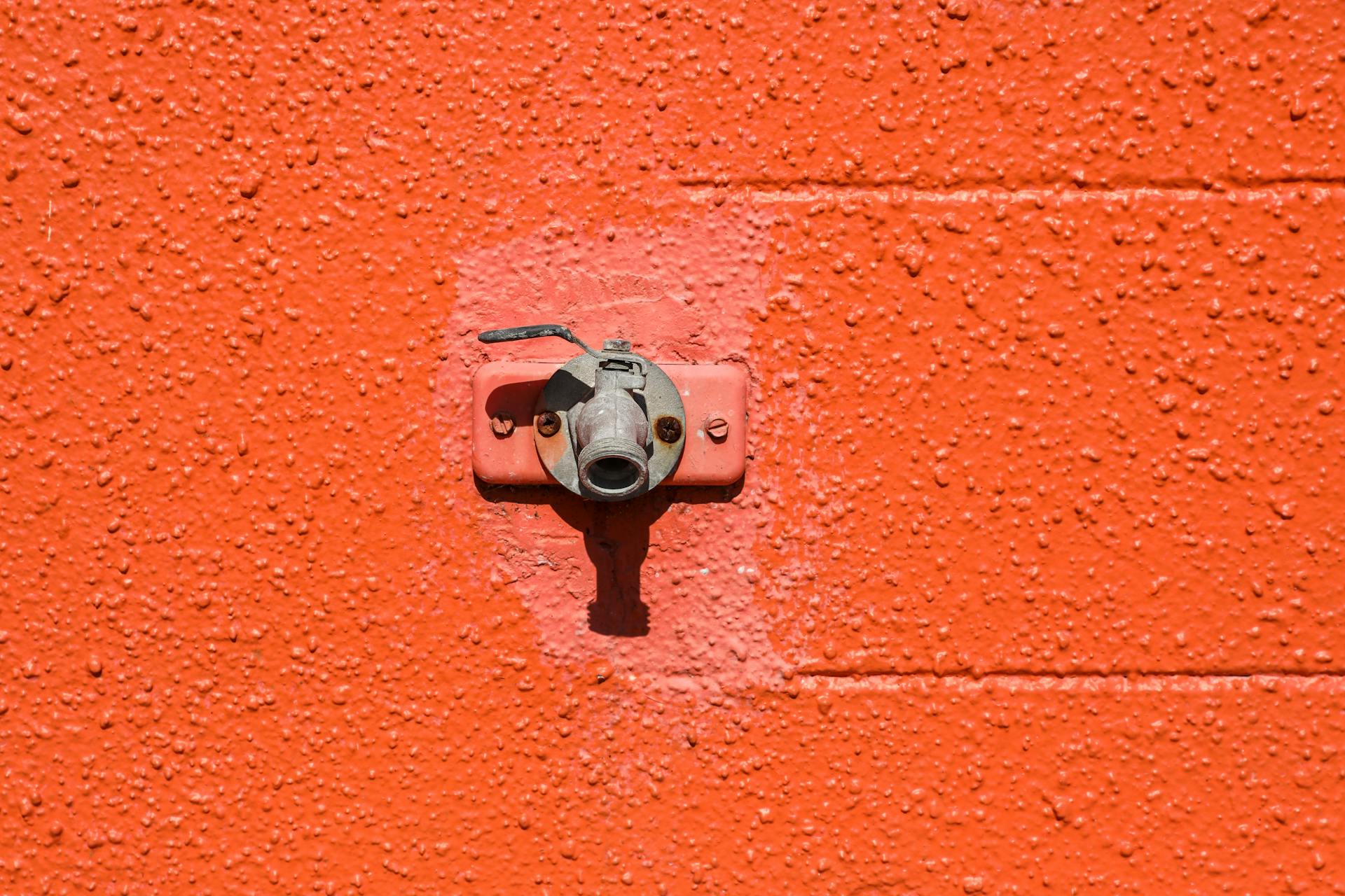 Detailed shot of a textured orange wall featuring an old faucet in Orlando, Florida.