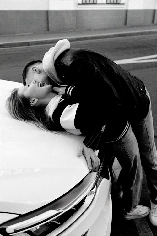 A Man and Woman Kissing in Front of a Car