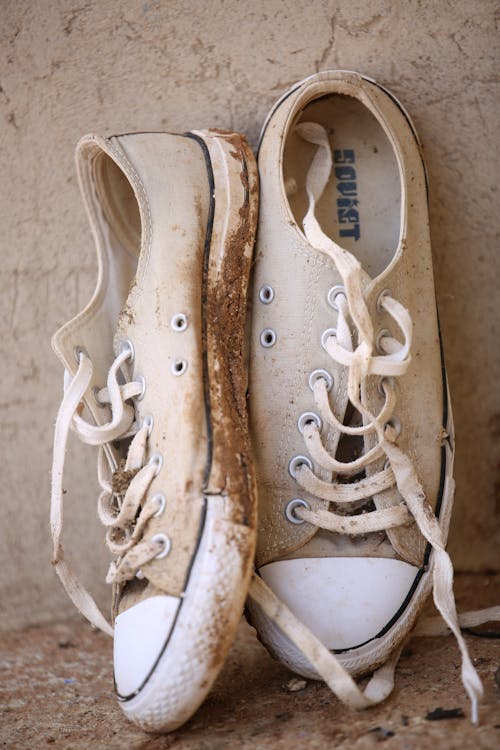 Muddy Footwear Beside a Wall
