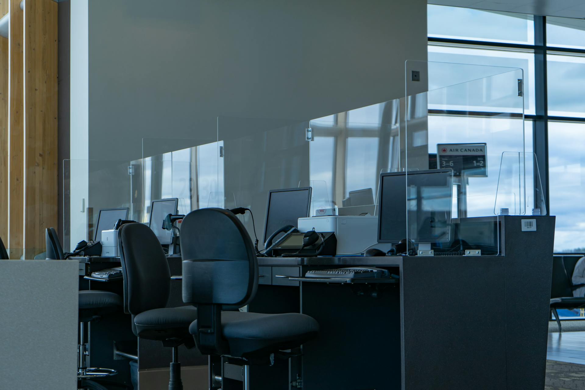 A contemporary airport boarding counter with glass dividers and computers, ready for passengers.