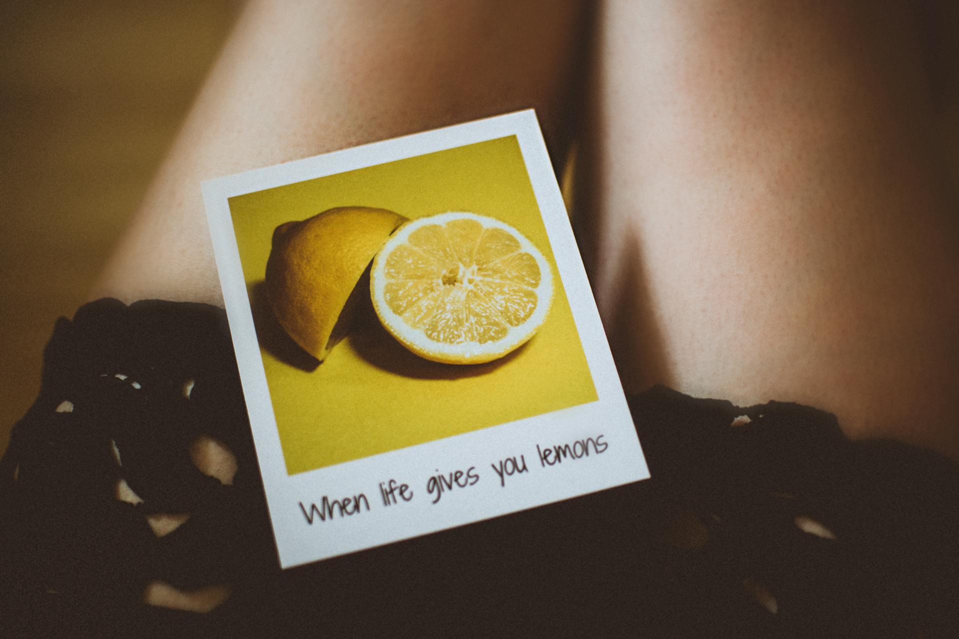 Artistic shot of a lemon-themed quote "When life gives you lemons" on a polaroid against a soft background.