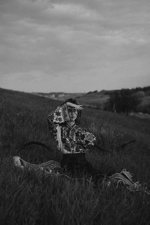 Grayscale Photo of Woman Kneeling on a Carpet on a Grass Field