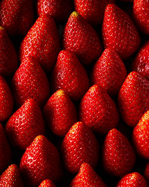Close-up shot of fresh, juicy strawberries with a vibrant red color arranged in a flat lay.
