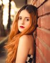 Woman in Black Tube Top Leaning on Brown Brick Wall