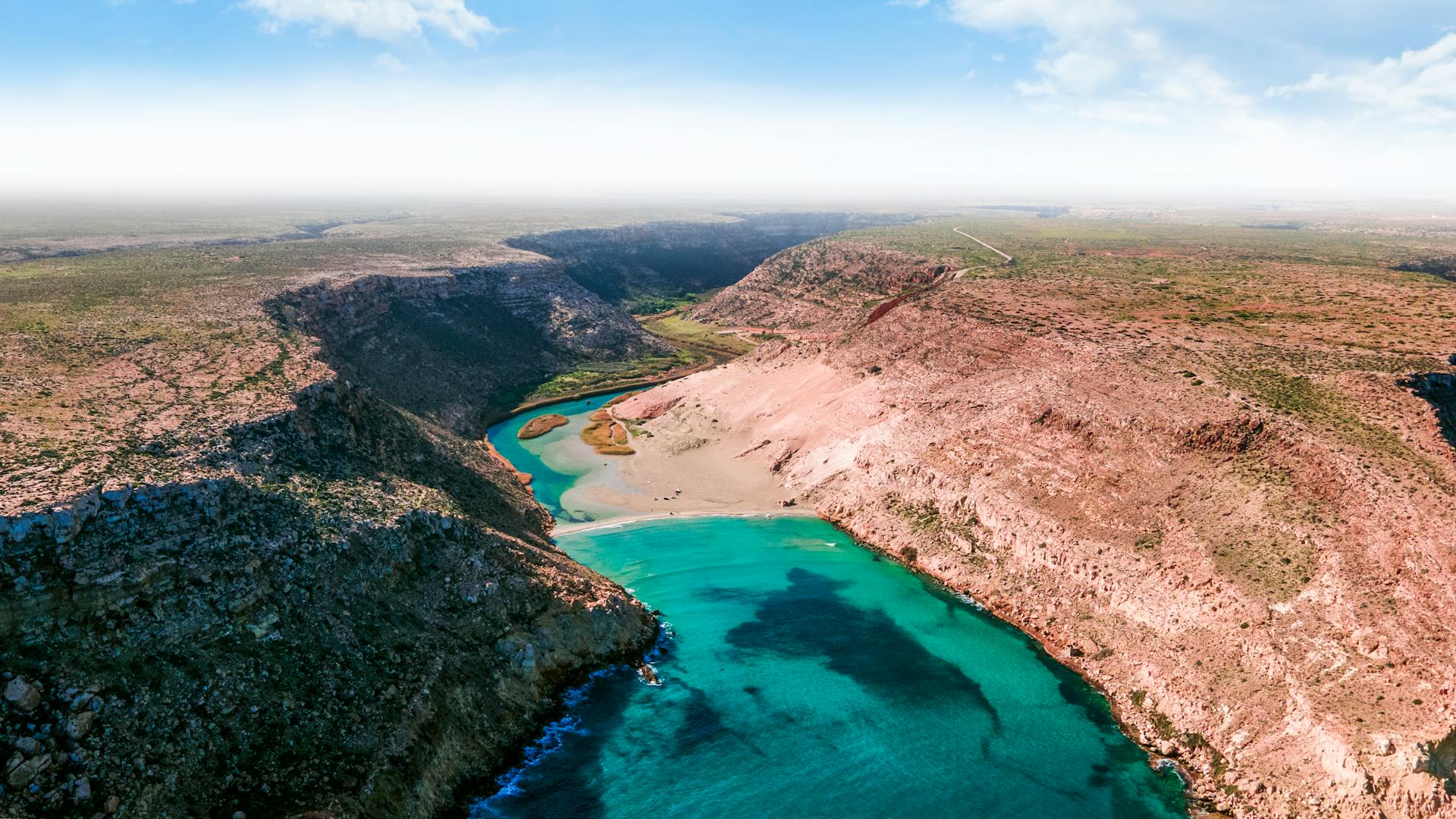 Stunning aerial view of Umm Ar Rizam, Libya's canyon landscape with turquoise waters.